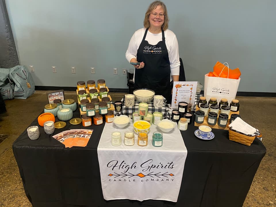 The High Spirits maker at a table of soy candles and gift bags